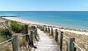 [Translate to Néerlandais:]  A scenic wooden boardwalk with rope railings cutting through sand dunes, near a luxury Les Castels campsite