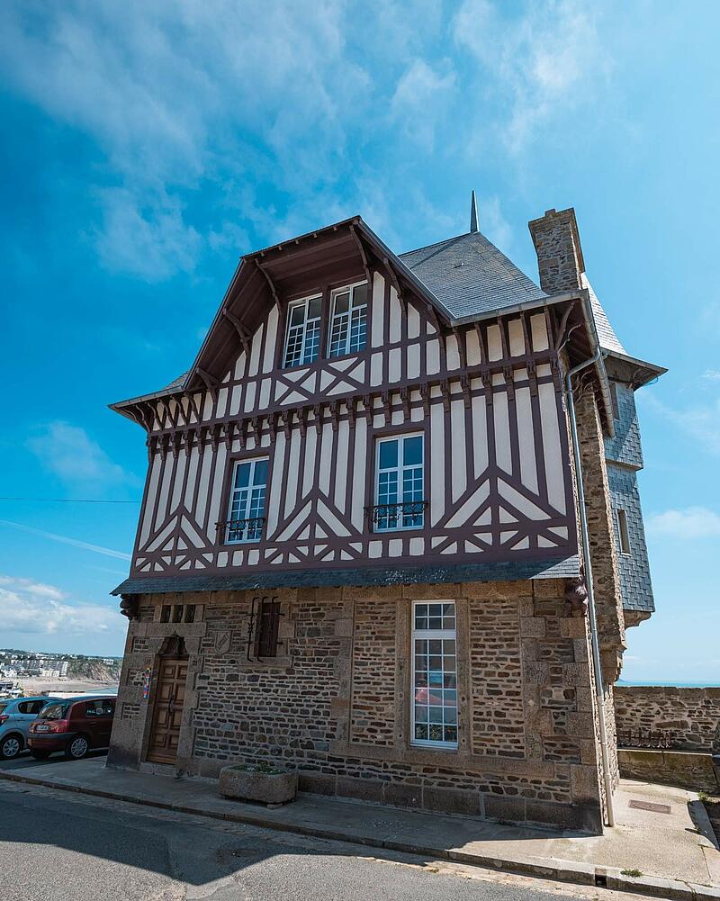 [Translate to Néerlandais:] A beautiful historic building combining a stone ground floor with upper levels featuring traditional half-timbered architecture, discovered while staying at Les Castels.