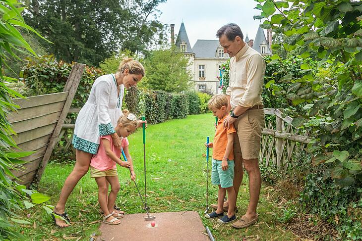 la ville-huchet, camping de luxe familial une famille jouant au mini-golf devant le château de la ville-huchet